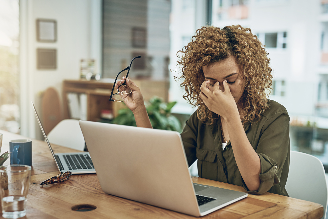 Shot of a young woman suffering from stress while using a computer at her work desk